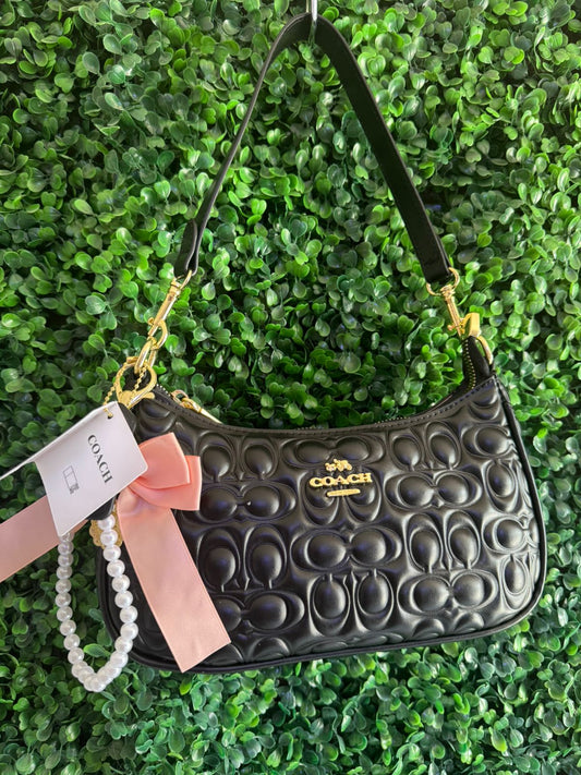 A BOLSA NOLITA COACH NEGRA CON LLAVERO DE PERLAS